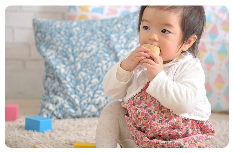 積み木（つみき）を口にする赤ちゃん。舐めても安全な塗料を使っているので赤ちゃんが口に入れても安全な積み木（つみき）です。