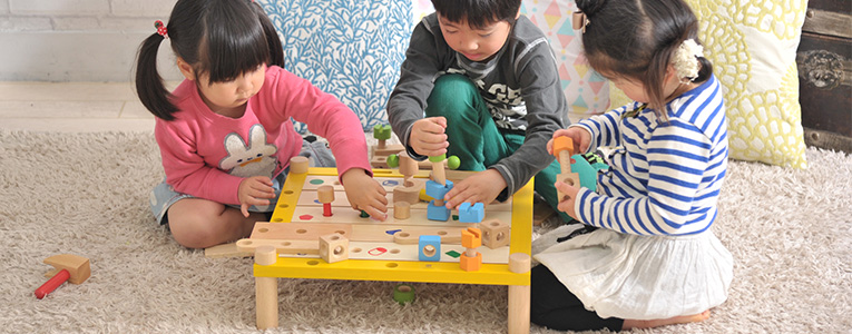 木のおもちゃで遊ぶ3歳の子ども